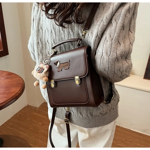 Detail of dark brown PU leather backpack featuring embroidered dachshund and vintage buckles