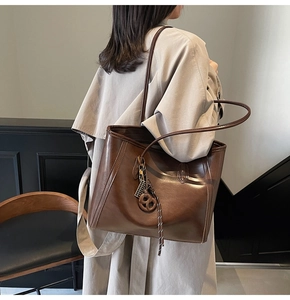 Detailed view of a dark brown vintage leather tote bag worn with a beige trench coat