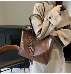 Deep brown leather tote bag with long shoulder handles shown in a lifestyle office setting