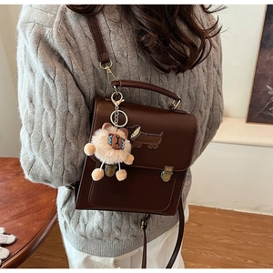 Detail of vintage brown shoulder bag featuring embroidered dachshund and lion plush charm
