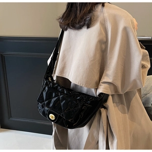 Detail of glossy black quilted shoulder bag with gold rotating metal lock and strap