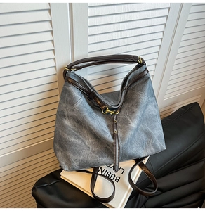 Detailaufnahme der Vintage-Tasche mit rauchgrauem Texturstoff und dunkelbraunen Lederriemen
