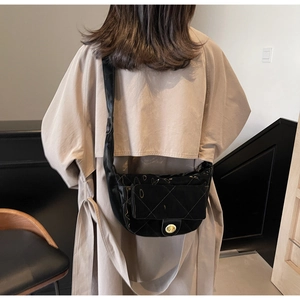 Detailed view of black quilted crescent crossbody bag with oval gold twist lock on shoulder
