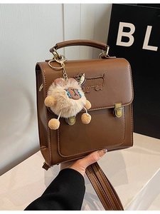 Brown leather vintage backpack with dog embroidery and plush cat charm held by hand