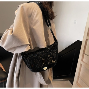 Close-up of black patent leather hobo bag with quilted pattern and gold twist lock