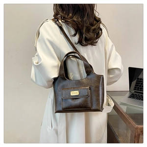 Détail du sac à main en cuir marron vintage avec logo en métal doré et poche latérale