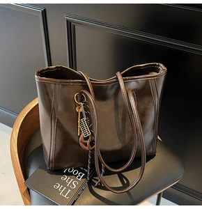 Detail of dark brown tote bag with metallic key and abacus charm on black wood