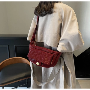 Detail of red patent leather saddle bag with diamond quilting and metal twist lock