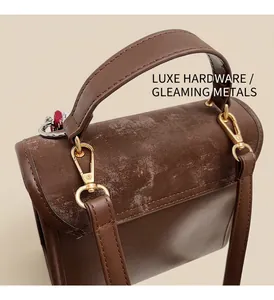 Dettaglio della pelle vintage marrone scuro e degli inserti in metallo dorato della borsa