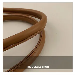 Gros plan de la poignée de sac en cuir marron avec texture fine et double couture