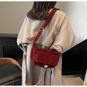 Deep red quilted saddle bag detail on model wearing a classic khaki trench coat