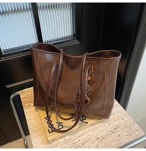 Close-up of brown faux leather tote with fine stitching and vintage abacus charm detail