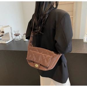 Close-up of brown quilted shoulder bag with glossy finish and gold metal twist lock