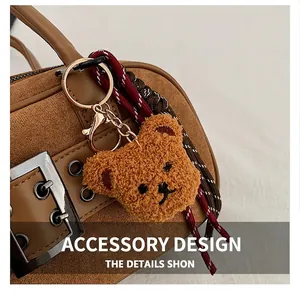 Détail d'un charm ours en peluche marron avec lanière tressée sur un sac rétro