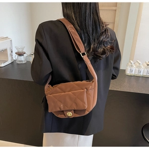 Brown quilted saddle bag detail showing golden twist lock and wide shoulder strap
