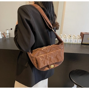 Close-up of brown quilted patent leather saddle bag with gold-tone twist lock detail