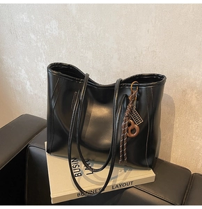 Detail of black faux leather tote bag with unique vintage abacus tassel charm