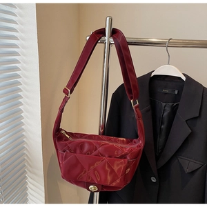 Detail of burgundy quilted patent leather saddle bag with gold-tone twist lock closure