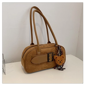 Détail du sac boston en daim marron avec boucle de ceinture et charmant ours peluche