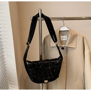 Detail of black quilted hobo bag featuring a gold twist lock and velvet texture