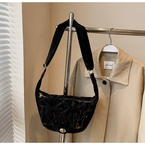 Close-up of black quilted dumpling bag with gold hardware and wide shoulder strap