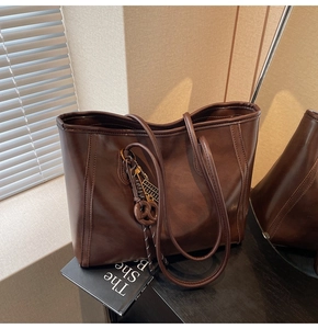 Close-up of deep brown leather tote bag with elegant knot pendant and glossy finish
