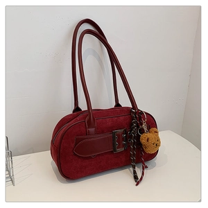 Détail du sac boston en daim bordeaux avec sangle décorative en cuir et boucle argentée