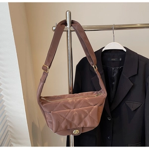 Detail of dark brown quilted saddle bag with metal twist lock and gold zipper closure