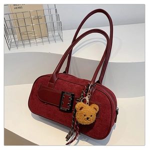 Vue détaillée du sac en daim bordeaux avec sangles en cuir et charm ours peluche