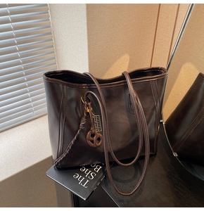 Detail of dark brown tote bag with decorative abacus pendant and woven knot detail