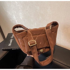 Close-up of coffee brown quilted puffer saddle bag with glossy nylon and gold clasp
