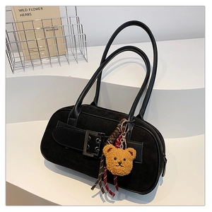 Détail du sac à bandoulière en daim noir avec boucle rétro et breloque ours en peluche