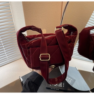 Close-up of deep burgundy quilted patent leather with gold hardware and mini charm bag