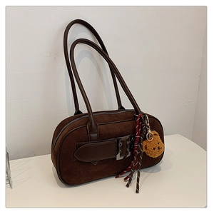 Détail d'un sac Boston en daim marron foncé avec boucles en cuir et charm ours en peluche