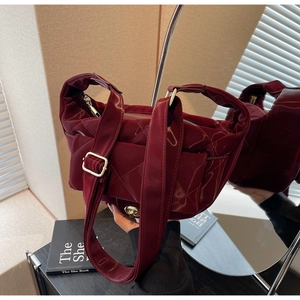Close-up of burgundy quilted saddle bag with glossy finish and gold metal buckle