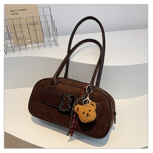 Détail d'un sac à bandoulière marron vintage avec un ours en peluche et un ruban