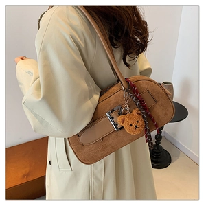 Détail du sac à bandoulière en daim marron avec boucle argentée et breloque ourson