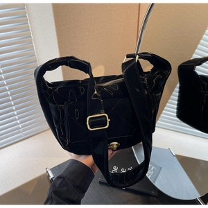 Detail of glossy black quilted shoulder bag with gold twist lock and adjustable wide strap