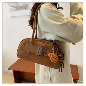 Détail du sac sous le bras en daim marron avec boucle en métal et pendentif ours