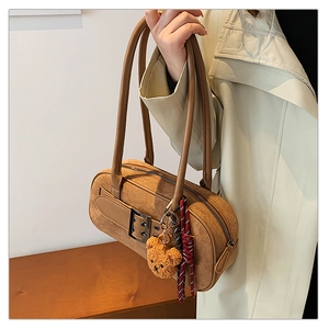 Détail du sac Boston en daim marron avec doubles bretelles et pendentif ours en peluche