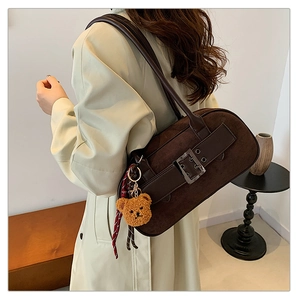 Sac bandoulière en daim marron porté avec breloque ours et détail d'écharpe rayée