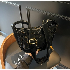 Detail of black quilted patent leather handbag with gold metal lock on a leather chair