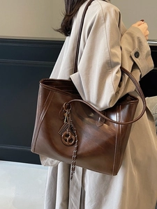 Deep brown oversized retro tote bag with pretzel charm and glossy leather texture