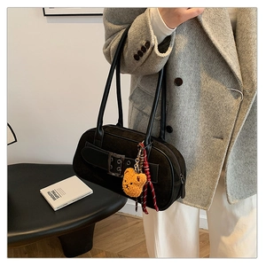 Détail du sac porté épaule rétro noir avec boucle métal et breloque ours en peluche