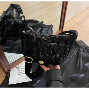 Close-up of black quilted patent leather bag with gold twist lock and adjustable strap