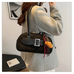 Détail du sac rétro noir avec sangle à boucle et breloque ours en peluche sur l'anse