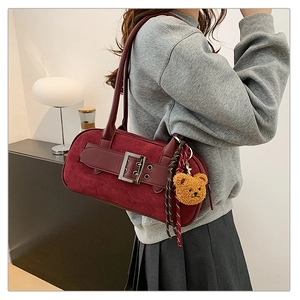 Détail du sac bandoulière vintage bordeaux en daim avec boucle et pendentif ourson