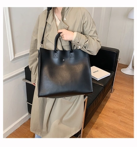 Close-up of a large black tote bag featuring reinforced handles and magnetic closure