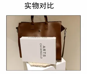 Brown leather tote bag featuring a vintage metal buckle and a removable long shoulder strap