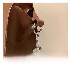Detail of silver metal swivel hook and rivet on dark brown leather tote bag strap